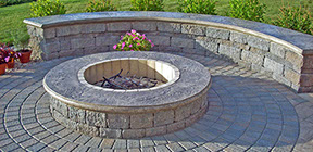 Custome Firepit with sitting wall landscaping behind and circle kit pavers